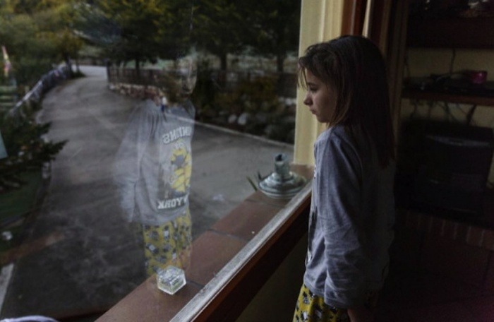 Nadia, mirando por el ventanal de su casa | Fotografía: Carlos García Pozo | Imagen agregada de El Mundo.